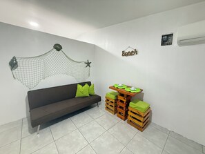 A room with a dark brown sofa, green cushions, a small wooden table with green cushions, a wall-mounted hammock, and a wall decoration with a star and the word 'Beach'. - Walking from Chipipe beach studio for 4with AC in charming Salinas (Salinas)