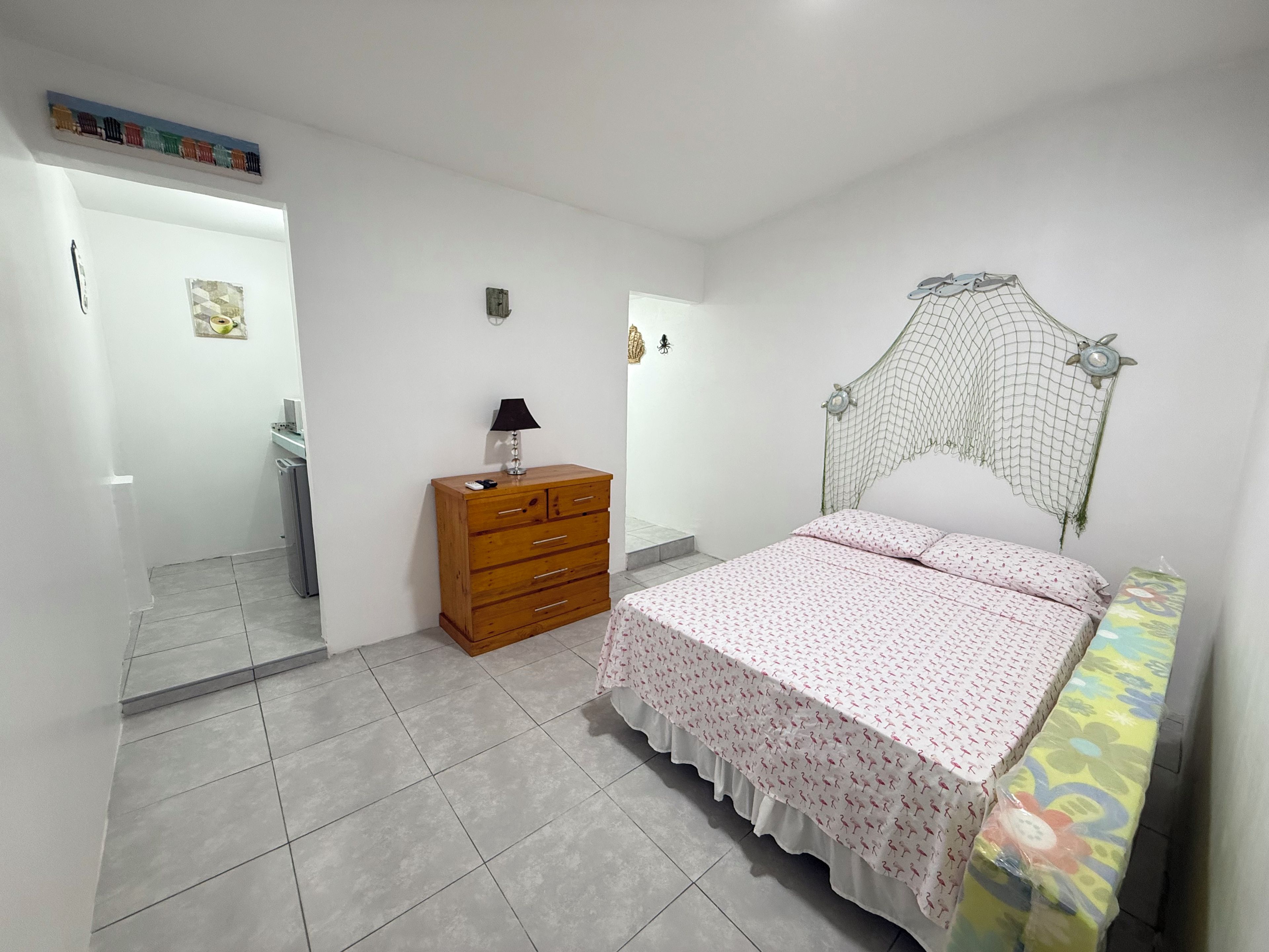 Un dormitorio con una cama, un aparador de madera, una mesita de noche y un espejo.