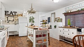 Una cocina con armarios blancos, encimera de madera, una araña y un letrero que dice 'A Place Called Dwell'.