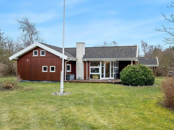 A two-story house with a red exterior, a chimney, and a covered porch. - 4 Star Holiday Home in Nakskov (Nakskov)