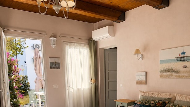 A bedroom with a bed, a nightstand, a lamp, a window, and a door. - Byzantine Villa (Ravenna)