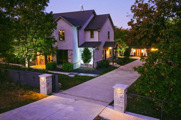 A two-story house with a driveway, a stone wall, and a well-maintained lawn. - DFW Penrose House Swim-Up Bar Estate Sleep 28 | Weddings | Hot Tub | Mini Golf (Princeton)