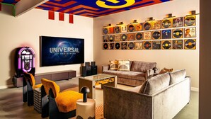 Uma sala de estar moderna com uma grande televisão de tela plana, uma mesa de pebolim e uma parede de discos de vinil.