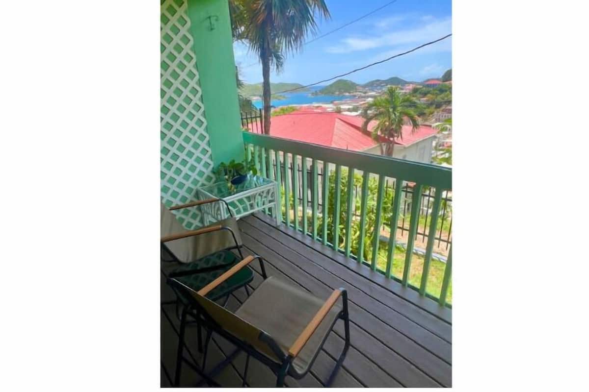 Un balcón con vista a la costa, que incluye una mesa y sillas de madera.