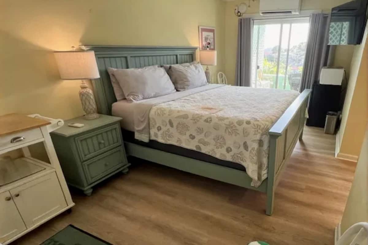 Un dormitorio con cama, mesitas de noche, cómoda y un tapete verde, además de una toalla verde y blanca.
