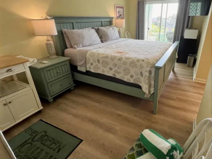 Ein Schlafzimmer mit Bett, Nachttischen, Kommode, einer grünen Matte und einem grün-weißen Handtuch.