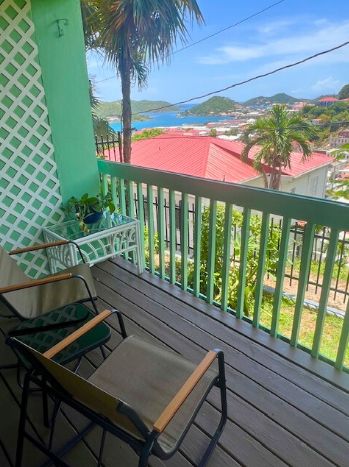 Varanda com vista para a costa, com uma mesa e cadeiras de madeira.