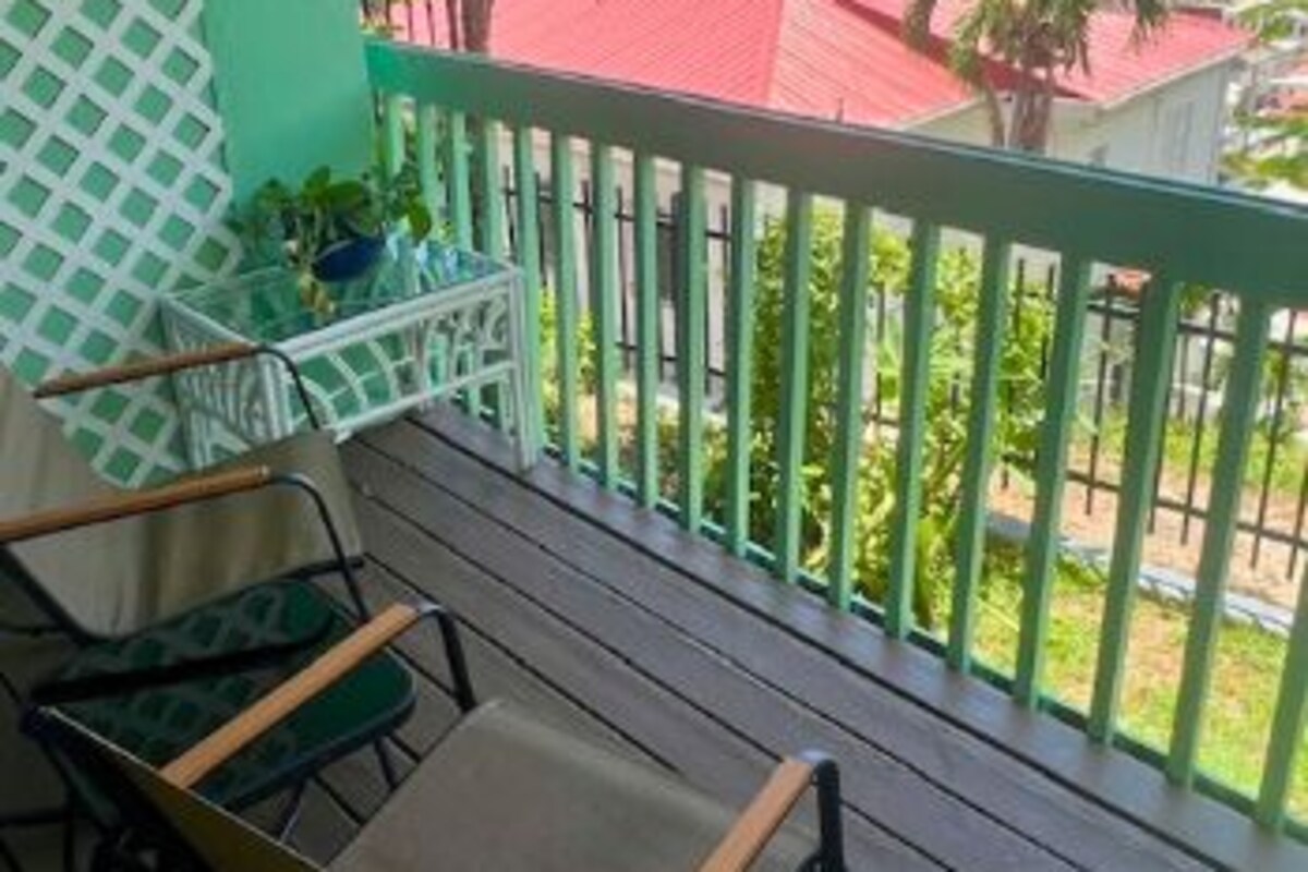 A balcony with a view of a coastal area, featuring a wooden table and chairs.