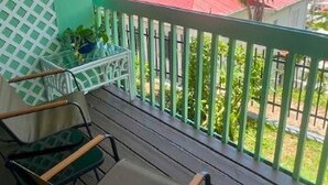 A balcony with a view of a coastal area, featuring a wooden table and chairs. - The Green Iguana Hotel (Charlotte Amalie)