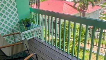 Varanda com vista para a costa, com uma mesa e cadeiras de madeira.