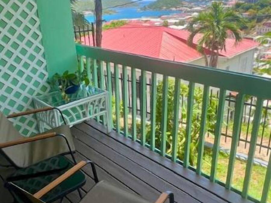 A balcony with a view of a coastal area, featuring a wooden table and chairs.