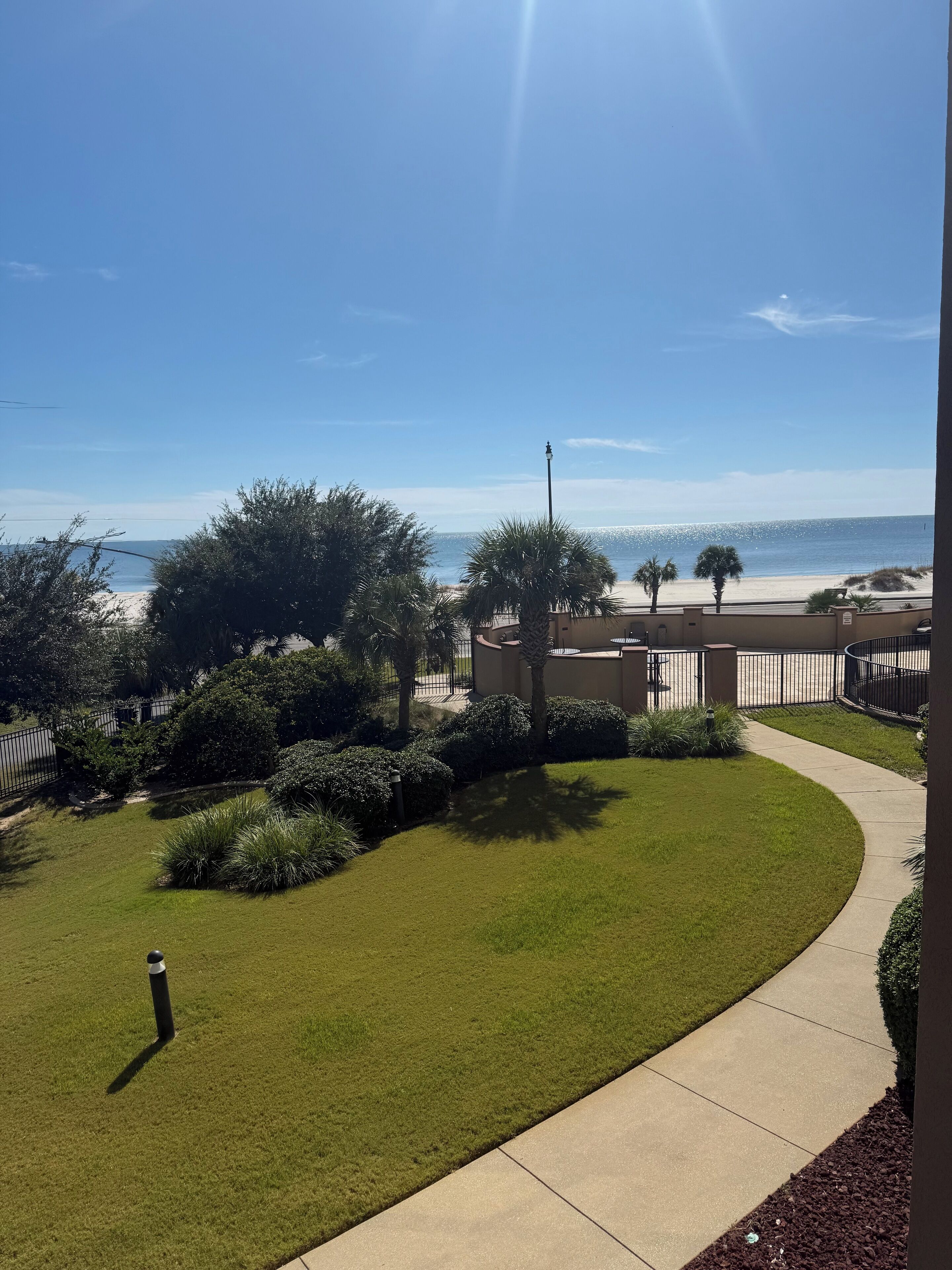 A well-maintained lawn with a curved pathway leading to a beach.