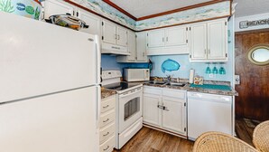Eine kompakte Küche mit weißen Schränken, einer Mikrowelle, einem Backofen und einem Geschirrspüler.