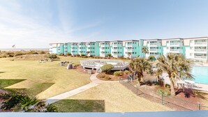 Ein mehrstöckiges Hotel mit Pool, angelegtem Rasen und blauem Himmel.