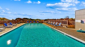 Una piscina azul cristalina con sillas de descanso y una terraza de madera.