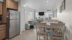 Una cocina moderna con armarios de madera, un refrigerador de acero inoxidable y un comedor con una mesa y sillas de madera.