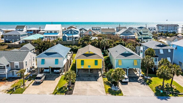 Un quartier résidentiel situé sur la côte, avec des maisons, un ciel dégagé et une vue sur l’océan.
