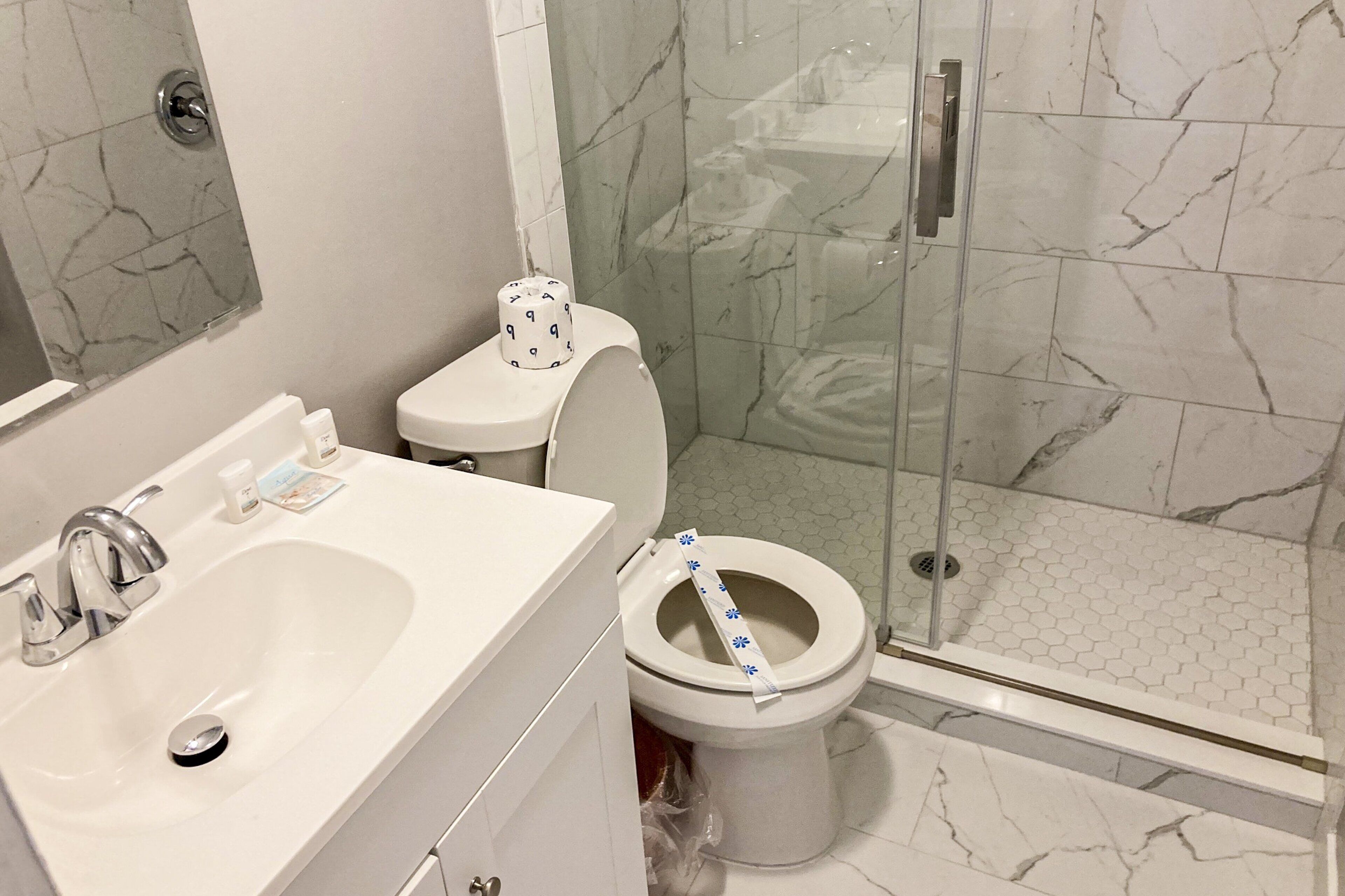Un bagno con lavandino, WC e doccia, tutti in bianco.