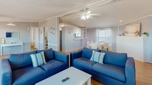 Un salon moderne avec deux canapés bleus, une table basse blanche et un ventilateur de plafond.