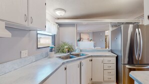 Une cuisine moderne avec des meubles blancs, un réfrigérateur en acier inoxydable et un évier.