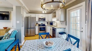 Una cocina moderna con armarios blancos, electrodomésticos de acero inoxidable y una zona de comedor azul.