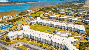 Ovenfra set boligkompleks med flere lejlighedskomplekser, et grønt område i midten og en strand i nærheden.