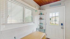 Une pièce avec un plafond en bois, une porte blanche dotée d’une petite fenêtre, une table et une chaise.