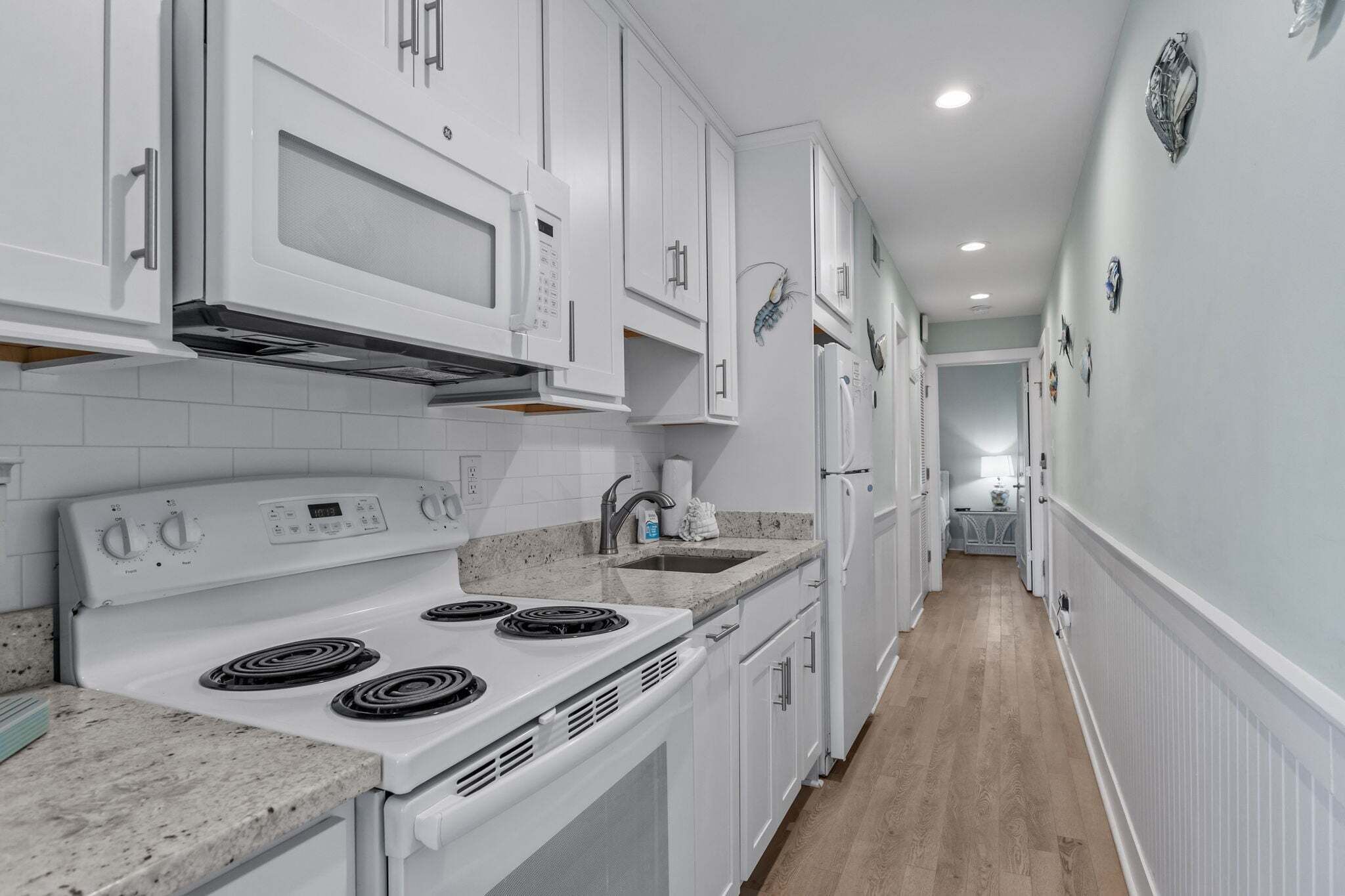 A kitchen with white cabinets, a stove, and a sink.