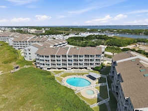 Un hôtel à plusieurs étages doté d’une piscine, entouré de verdure et offrant une vue sur la mer.