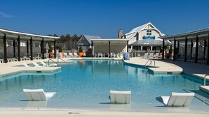 Une piscine avec des chaises longues et, au fond, un bâtiment portant l’inscription « Traders ».