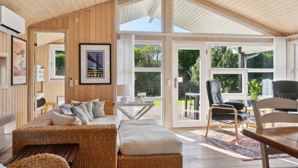 Un salón amplio con techo alto, paredes de madera y grandes ventanales con vistas al exterior.