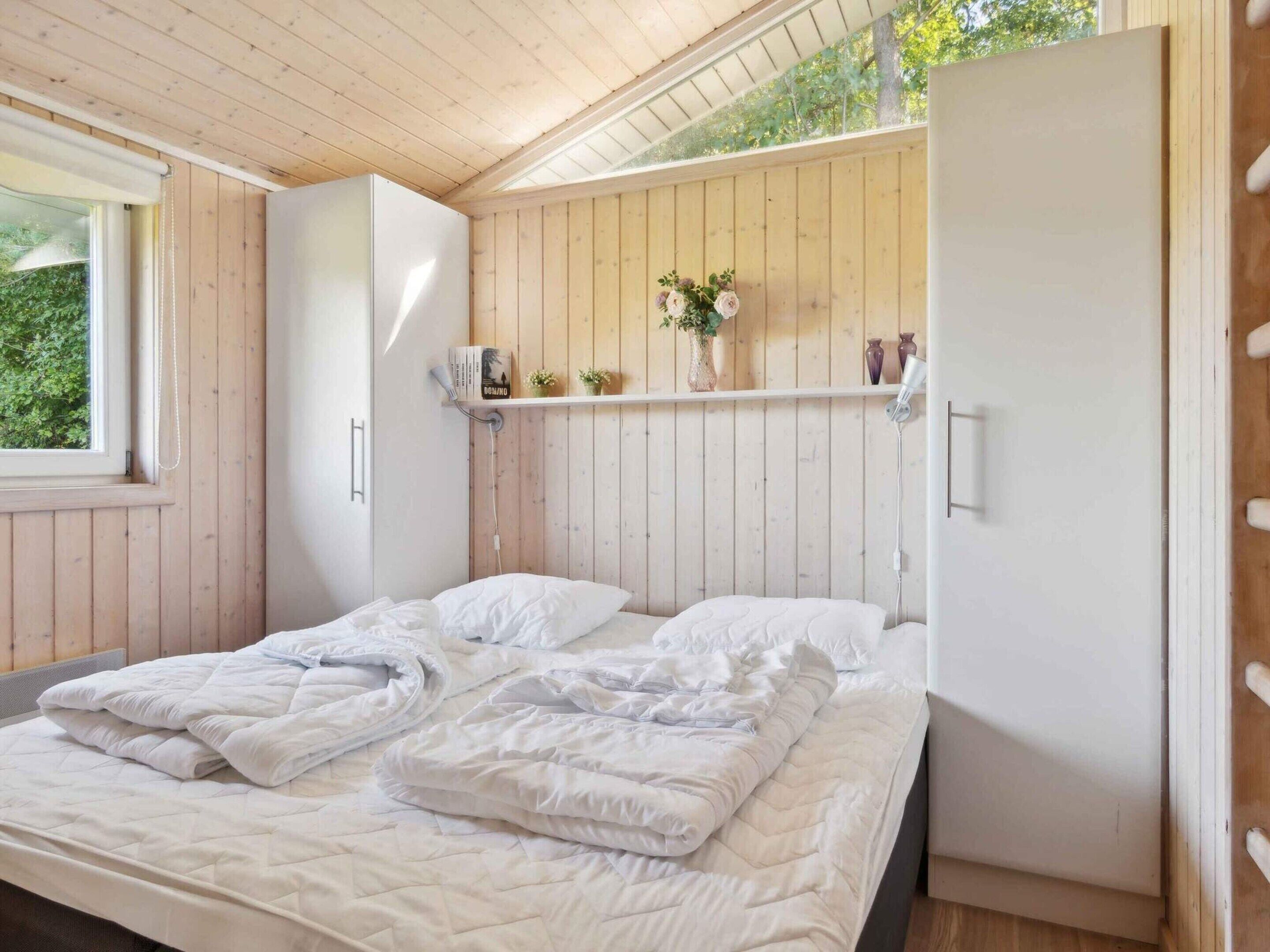 Une chambre à coucher comprenant un lit, une armoire, une étagère avec des objets décoratifs et une fenêtre.