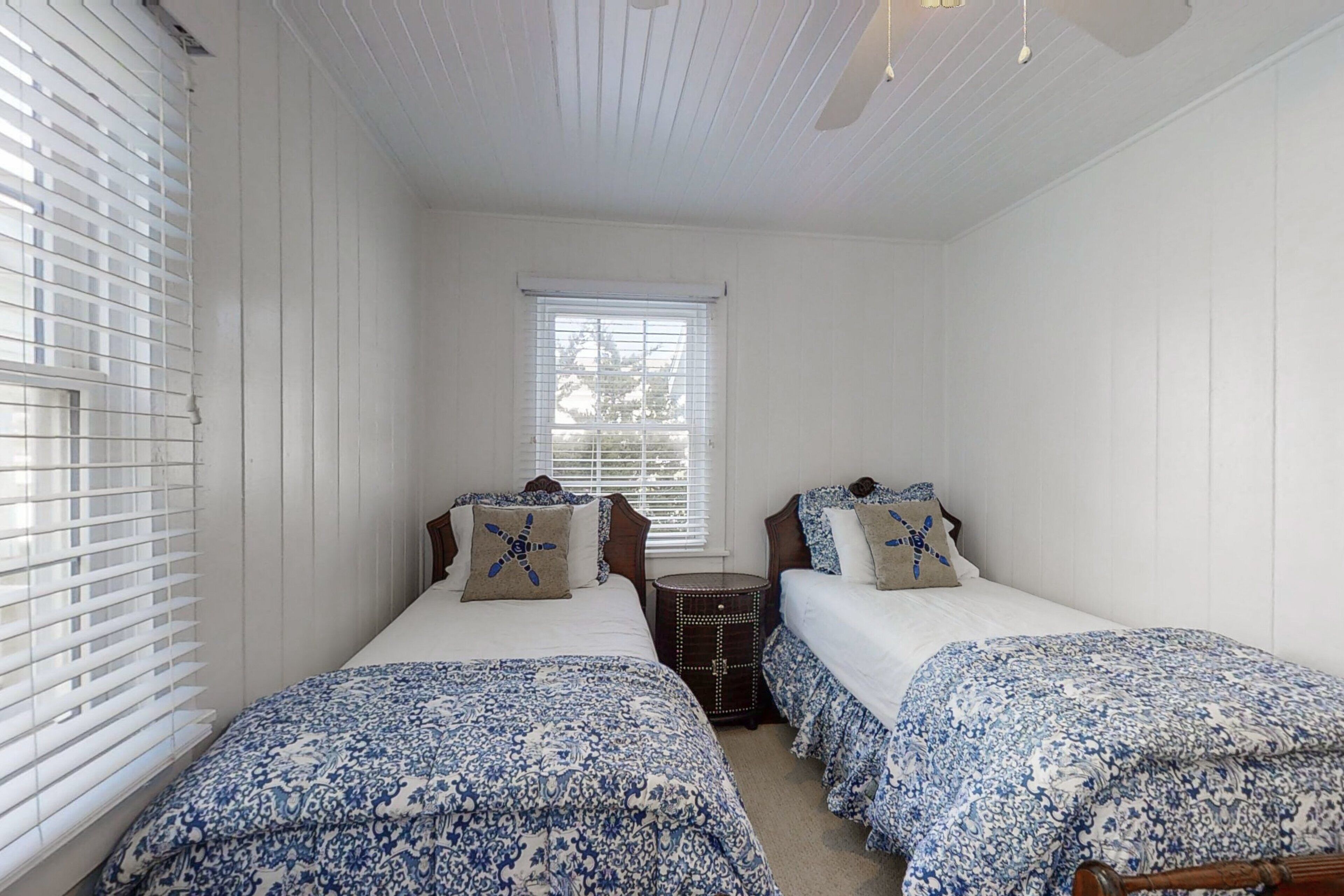 A bedroom with two beds, a window, and a small wooden chest.
