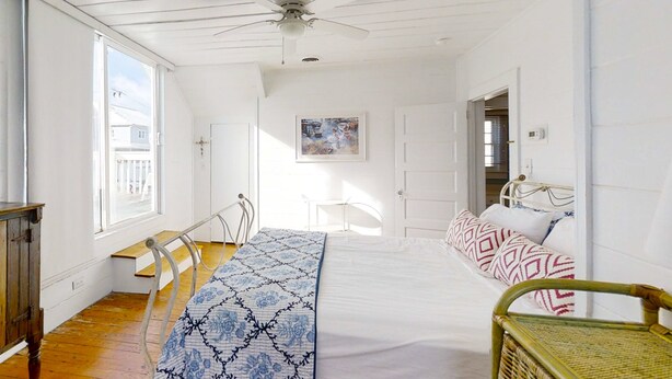 A bedroom with a bed, a chair, a desk, and a window. - Bullard Cottage: In the heart of Atlantic Beach w/ocean views (Atlantic Beach)