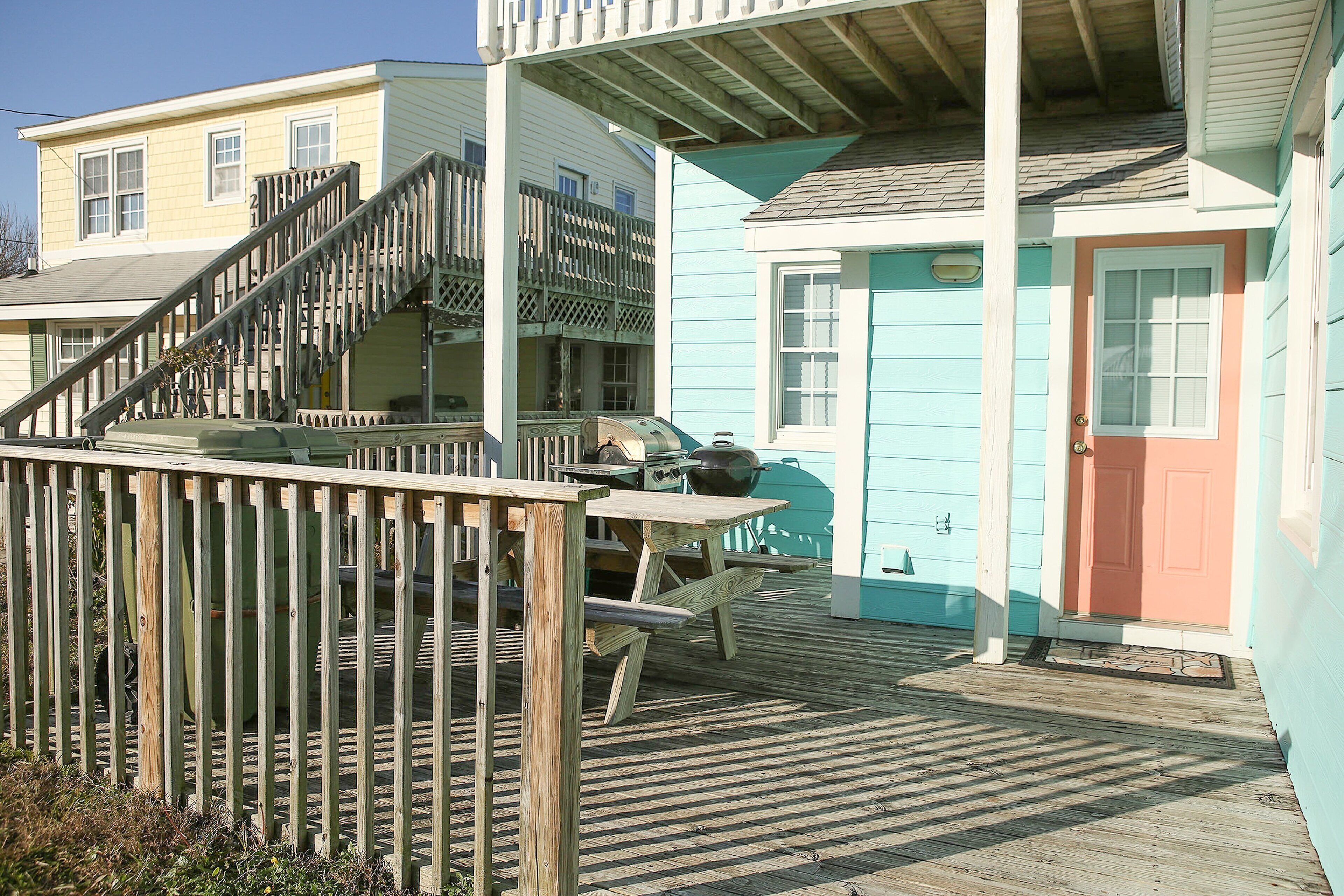 A wooden deck with a picnic table and a barbecue grill.