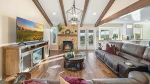 Amplia sala de estar con chimenea, televisor grande y sofá de cuero.