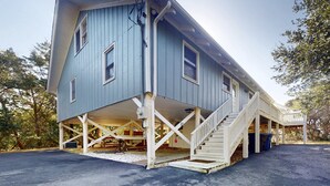 A two-story house with a porch and a staircase leading to the upper floor. - 3rd-row beach cottage with ocean views, beach access, deck, & grill (Emerald Isle)
