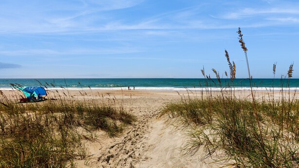 Ein Strand mit einem Zelt und Menschen in der Ferne.