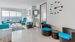 A modern living room with a large window, a flat-screen TV, and a wall clock.