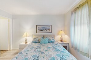 A bedroom with a bed, two bedside tables, a nightstand, a framed picture on the wall, and a window with curtains. - 3rd-Floor Condo in Oceanfront Building w/Ocean Views, Shared Pool, Free WiFi (Atlantic Beach)
