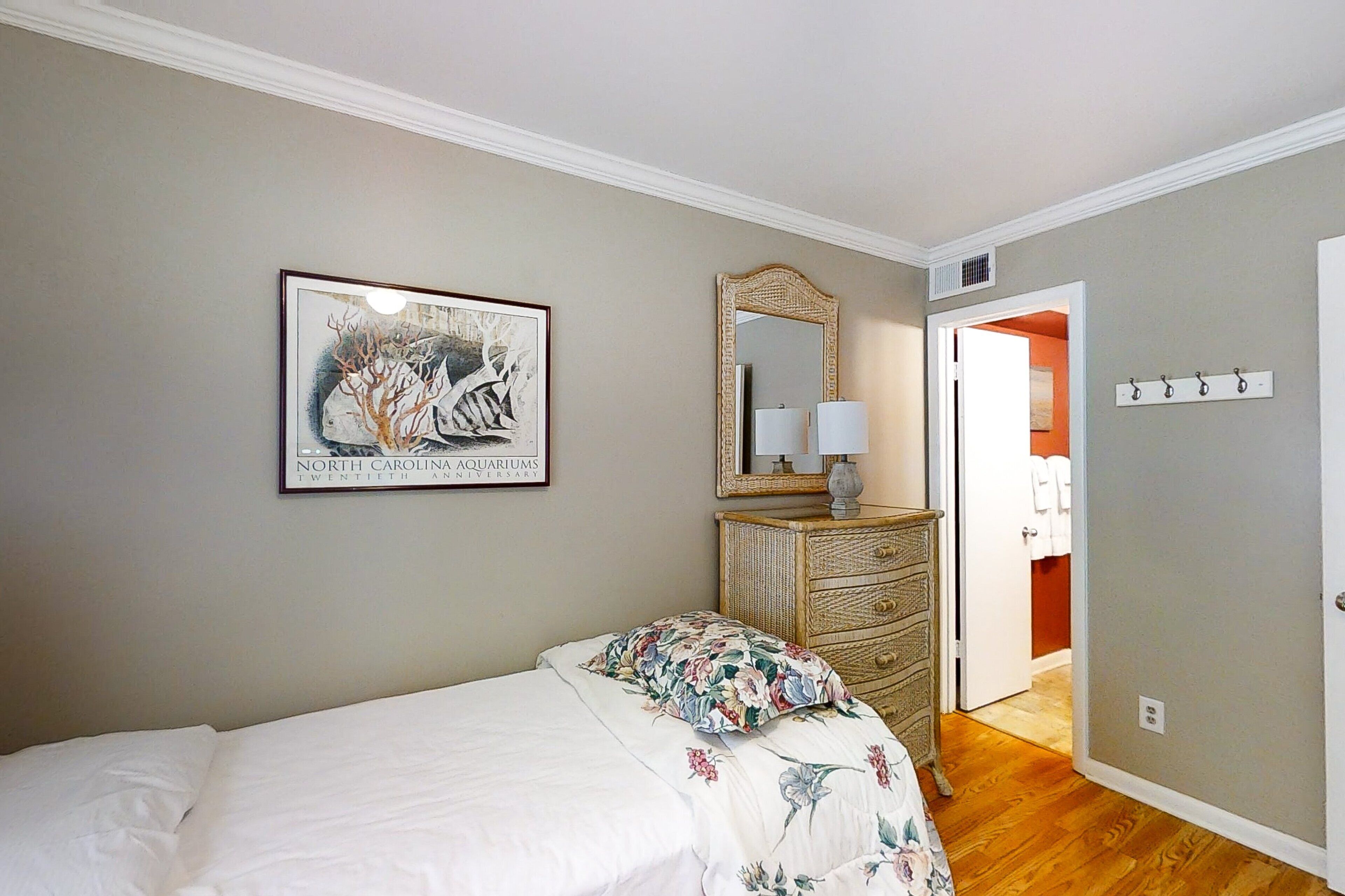 A bedroom with a bed, dresser, mirror, and a framed picture on the wall.
