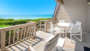 A wooden deck with a view of the ocean, white outdoor furniture, and a railing. - Multi-Level, Oceanfront Condo in Pine Knoll Shores w/Free WiFi, Shared Pool (Pine Knoll Shores)