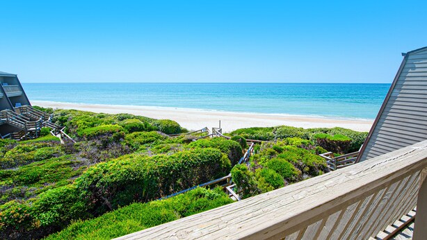 A beach view from a balcony with a wooden railing, a sandy beach, and the ocean. - Multi-Level, Oceanfront Condo in Pine Knoll Shores w/Free WiFi, Shared Pool (Pine Knoll Shores)