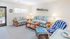 A living room with two sofas, a coffee table, and a wicker chair. There are two lamps on side tables. - Multi-Level, Oceanfront Condo in Pine Knoll Shores w/Free WiFi, Shared Pool (Pine Knoll Shores)