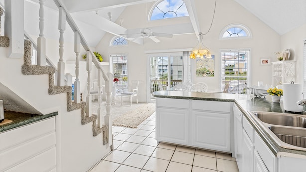 A spacious kitchen with a central island, white cabinetry, and a large window.