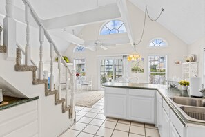 Une cuisine spacieuse dotée d’un îlot central, de meubles blancs et d’une grande fenêtre.