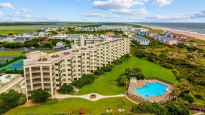 Un grand hôtel à plusieurs étages, doté d’une piscine et offrant une vue sur la plage.