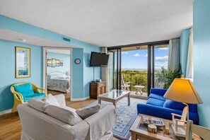 Una habitación con cama, sofá, mesa de centro, televisor y balcón con vistas.