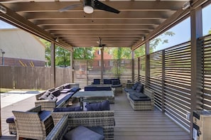 A covered outdoor seating area with wicker furniture and a ceiling fan.