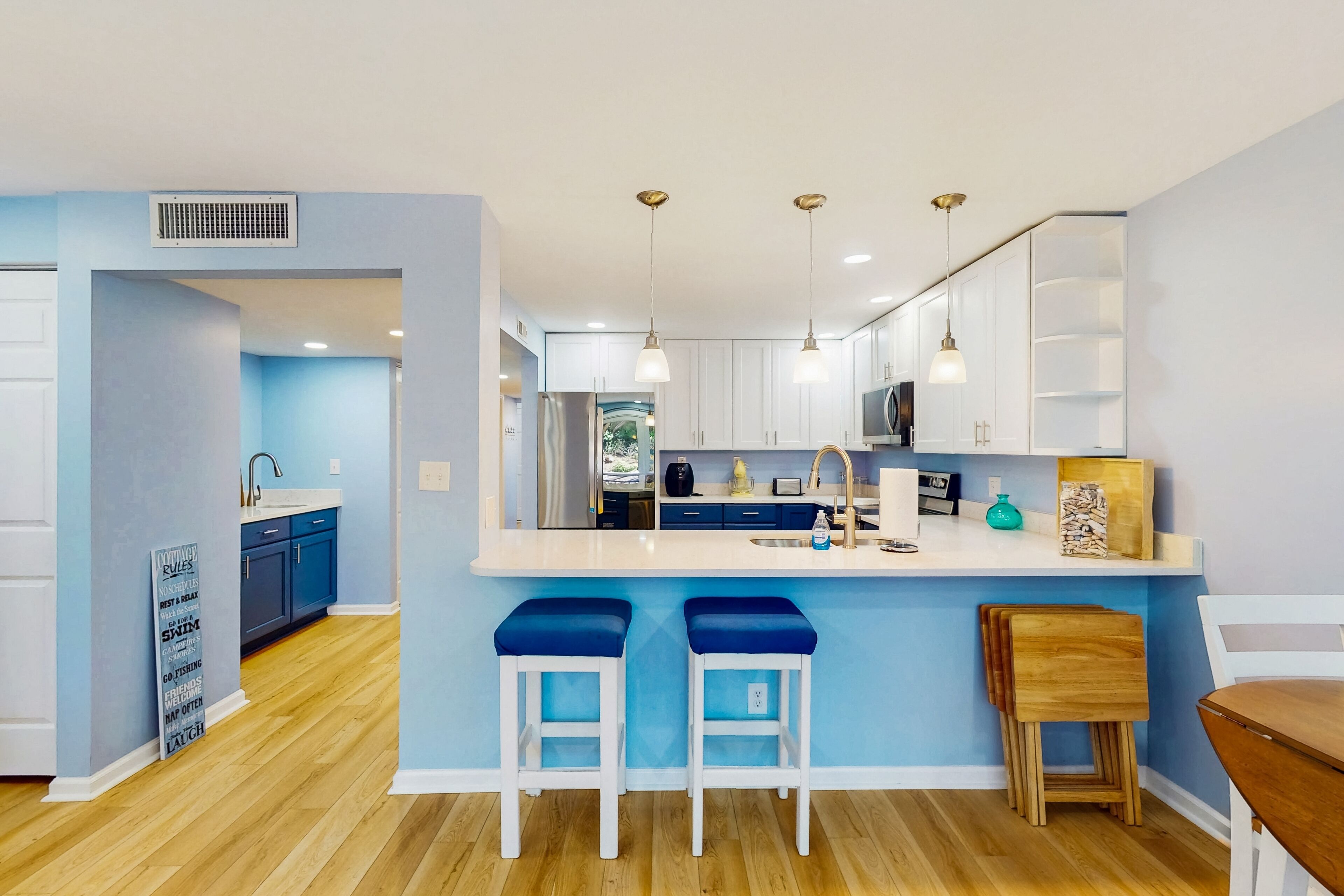 A modern kitchen with a central island, bar stools, and pendant lighting.